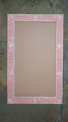 a pink and white frame sitting on top of a stone wall