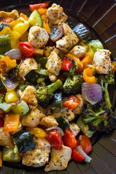 a plate filled with chicken, broccoli, peppers and onions on top of a table