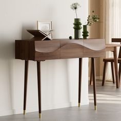 a wooden table with two vases on top of it next to a chair and wall