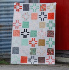 a quilt on the ground next to a red door