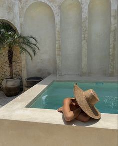 a woman in a hat sitting next to a pool