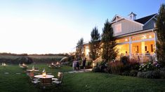 an outdoor dining area in front of a large house at night with lit candles on the tables