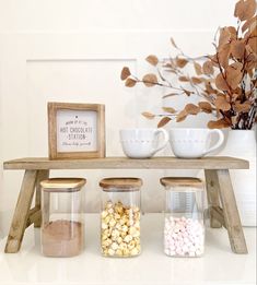 three jars filled with candy sitting on top of a wooden table next to a vase