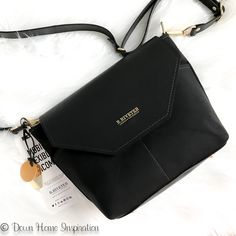 a black purse sitting on top of a white furnishce covered floor next to a tag