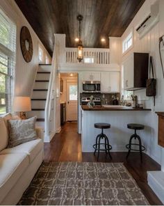 a living room and kitchen area in a small home with wood floors, white walls and ceilings