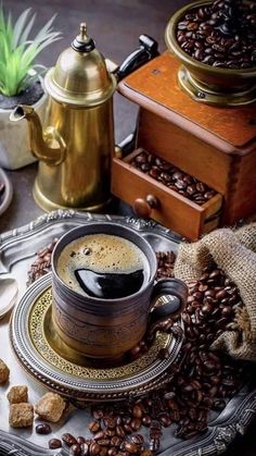 a cup of coffee sitting on top of a table next to some beans and other items