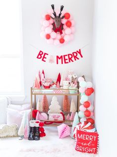 a christmas party with balloons and decorations on the wall, including a reindeer head hanging above it