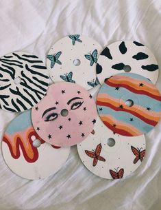 several buttons with different designs on them sitting on a white cloth covered bedding sheet