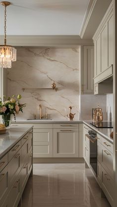 an elegant kitchen with marble counter tops and white cabinetry, along with gold accents