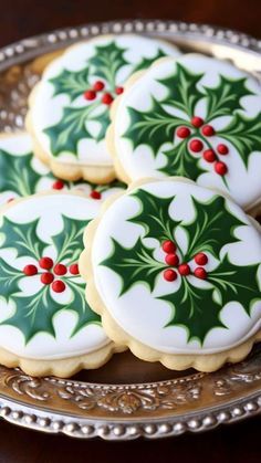 four decorated christmas cookies on a silver platter