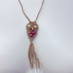 a necklace with beads and tassels hanging on a white wall in a room