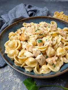 a plate full of pasta with chicken and parsley on the side next to a fork