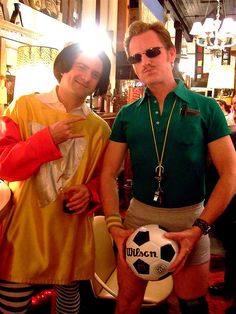 two men in costumes pose with a soccer ball