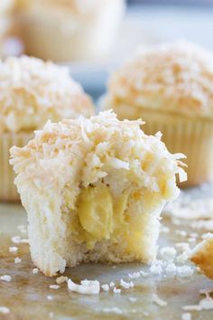 coconut muffins cut in half on a baking sheet with one bite taken out