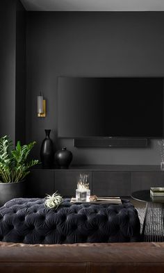 a living room with black furniture and a flat screen tv mounted on the wall above it