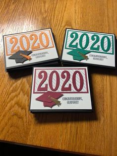 three magnets with graduation caps on them sitting on a wooden table next to each other