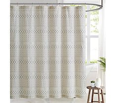 a white shower curtain with an arrow pattern on the front and side panels, hanging from a metal rod