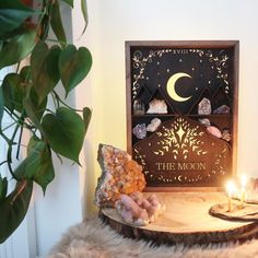 the moon is lit next to some rocks on a table with a candle in it