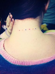 the back of a woman's neck with small dots on her left side and behind her ear