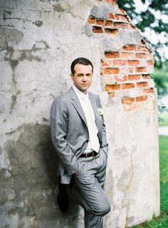 a man in a suit leaning against a wall