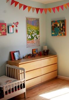 a baby's room with a dresser, crib and pictures on the wall