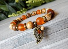 About the Bracelet Harmonize yourself with nature with this natural bead bracelet complimented by orange matte glass and a leaf charm. Bracelet Details: This orange and brown autumn bracelet is made with: ♥ 8mm Orange Matte Glass♥ 8mm Robles Wood♥ 8mm Picture Jasper♥ a Leaf Charm and two handmade charms All items are handmade and shipped within 1-3 business days. FREE U.S. SHIPPING ON ORDERS OVER $35 ON ORDERS OVER $35 Thank you for supporting small business. All designs are protected by copyrig Autumn Bracelet, Earthy Jewelry, Orange Bracelet, Natural Stone Beads, Natural Stone Bracelets, Fall Jewelry, Handmade Charms, Leaf Charms, I Love Jewelry