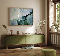 a painting hanging on the wall above a green cabinet in a room with wooden floors