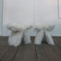 two white furry stools sitting on top of a wooden floor