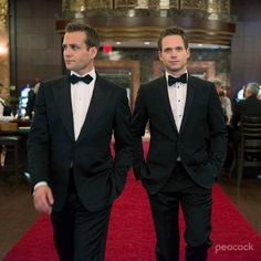 two men in tuxedos walking down a red carpet