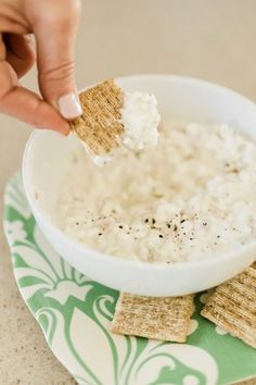 a person dipping crackers into a bowl of rice