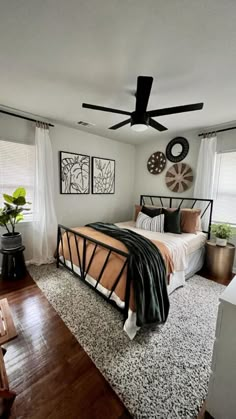 a bed room with a neatly made bed next to a window and a ceiling fan