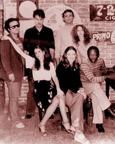 a group of people posing for a photo in front of a brick wall