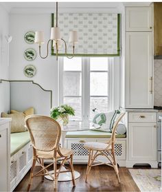 two wicker chairs sit in front of a window with green and white decor on it