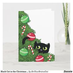 a christmas card with a black cat peeking out from the top of a green tree