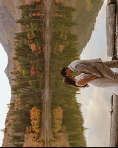 a man and woman standing next to each other in front of a body of water