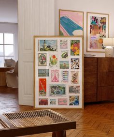 a room with wooden floors and pictures on the wall next to a table in front of a window