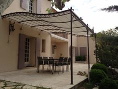 an outdoor dining area with table and chairs under a pergolated canopy over the patio