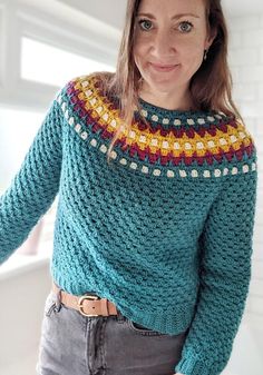 a woman wearing a blue sweater with multicolored crochet