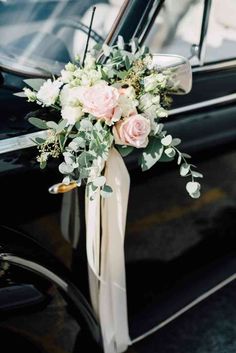 a bouquet of flowers is tied to the side of a black car with its door open