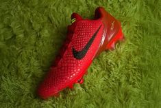 a pair of red nike soccer cleats on green grass