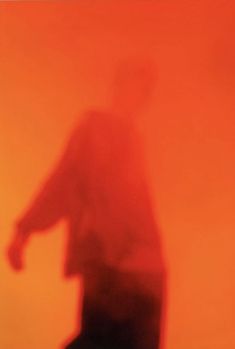 a blurry image of a man standing in the fog with his hand on his hip