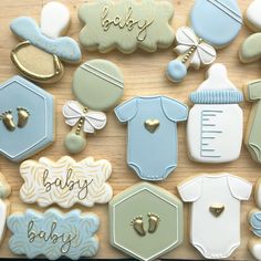 baby shower cookies are arranged on a wooden table with blue and white onesuits