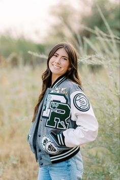 varsity jacket, senior pictures, senior girl poses, senior poses, graduation pictures, nature, green background, greenery Letterman's Jacket Outfit, Senior Pictures Outfits Sports, Cute Letterman Jacket Outfits, Senior Jacket Picture Ideas, Senior Picture Outfits Letterman, Senior Jersey Pictures, Lettermen Jacket Ideas