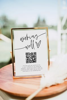 a sign that is sitting on top of a wooden table next to a white feather