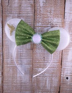 a green and white minnie mouse ears headband with a gold glitter bow on it