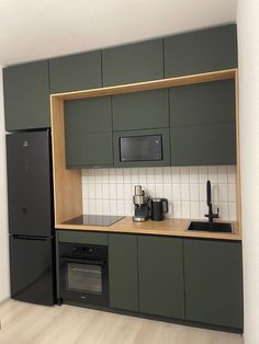 a kitchen with green cabinets and black appliances