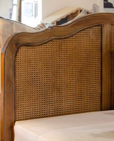 the headboard and foot board of a bed with wicker on it, in front of a mirror