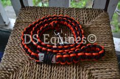 an orange and black leash sitting on top of a wicker chair next to a bottle opener