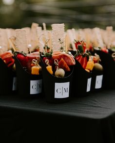 several trays filled with different types of food on top of a black cloth covered table