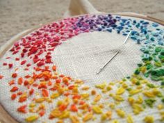 a close up of a colorful piece of cloth on a table with a needle in it